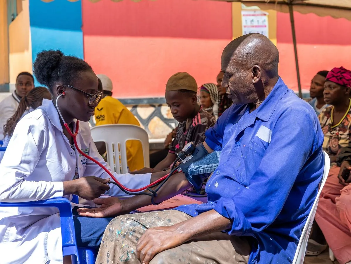 A health worker checking an elderly man's blood pressure