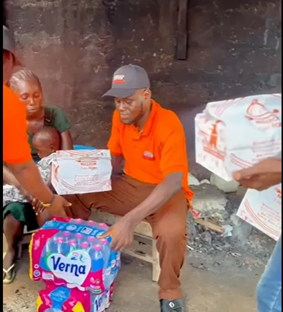 A volunteer handing a food pack to a seated woman